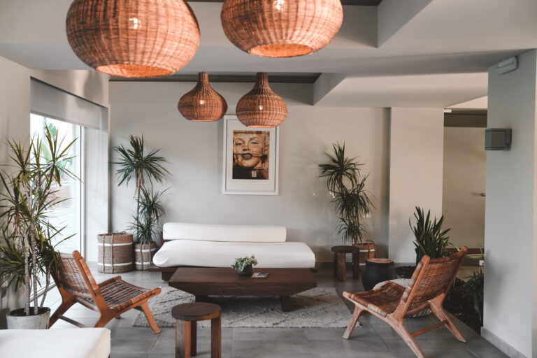 Ein stilvoll eingerichteter Lounge-Bereich mit warmen Naturtönen, gemütlichen Rattanmöbeln und handgefertigten Leuchten – eingerahmt von üppigem Grün.