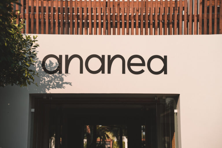Moderner Hoteleingang mit großem, schwarzem ‚ananea‘-Schriftzug auf heller Wand und Holzverkleidung im oberen Bereich.