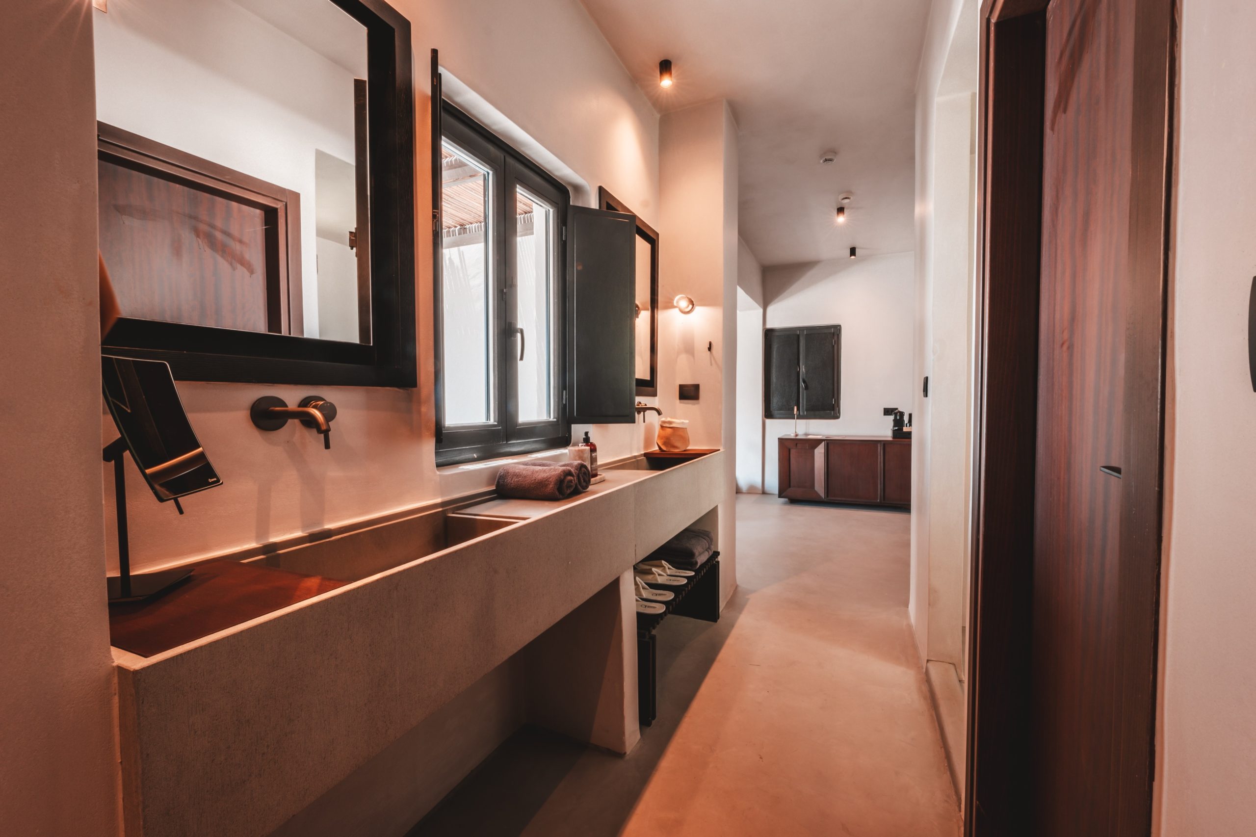 Modernes Badezimmer mit langem Waschbecken, Spiegel, Handtüchern und Fenster, minimalistische helle Einrichtung.