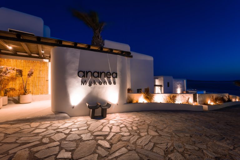 Beleuchteter Hoteleingang von „ananea Mykonos“ bei Nacht mit typischer weißer Architektur und Blick aufs Meer.