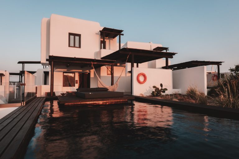 Weiße mediterrane Villa mit Hängematte und privatem Pool im Sonnenuntergang, moderne Architektur mit Holzdetails.