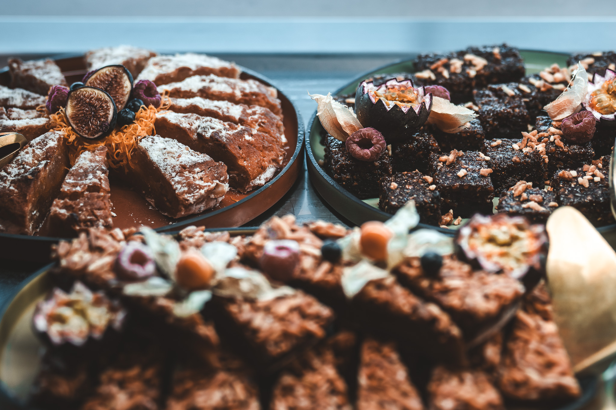„Auswahl an köstlichen Kuchen und Dessertwürfeln, liebevoll dekoriert mit frischen Früchten wie Feigen, Himbeeren und Physalis.“