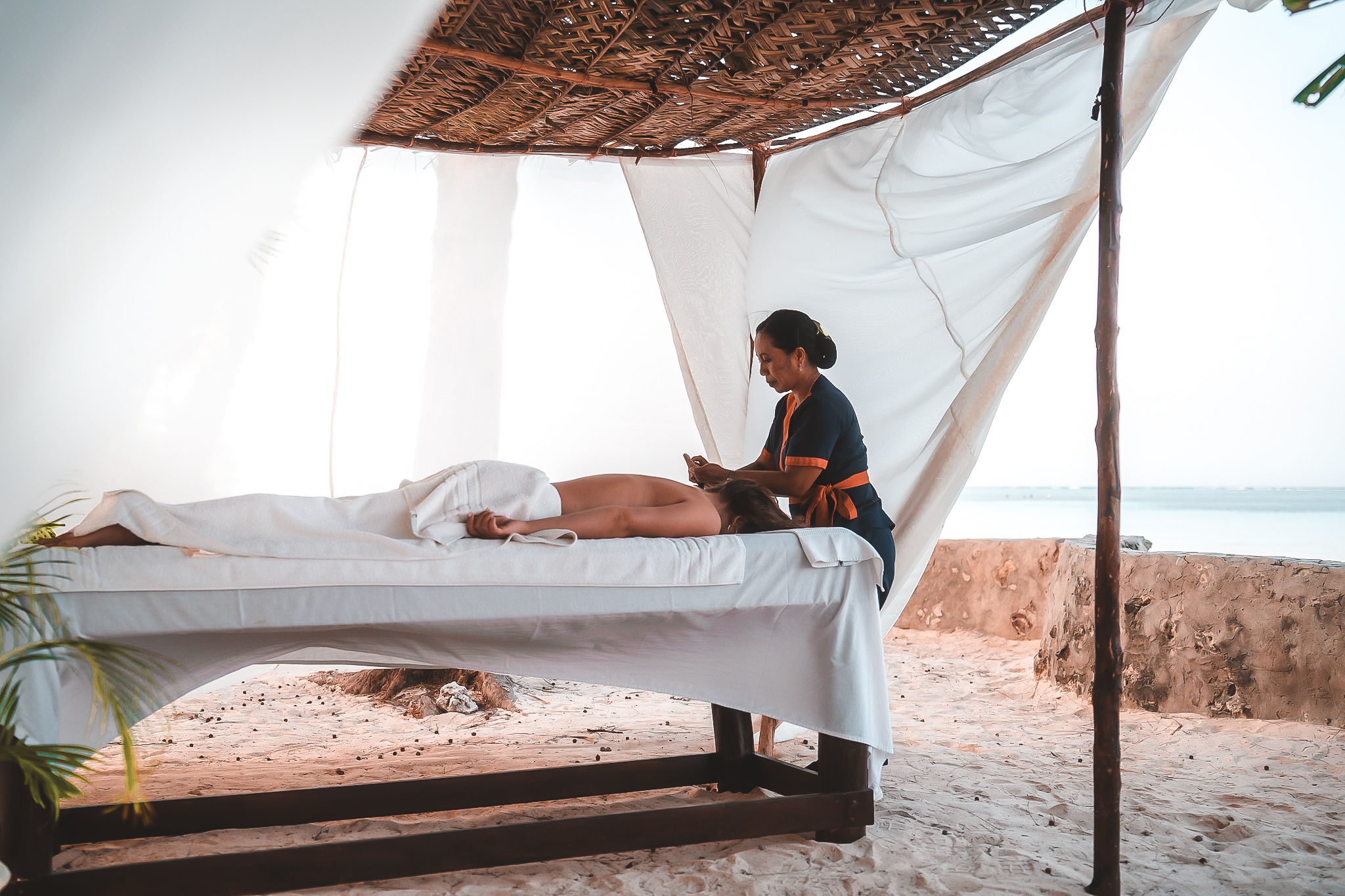 Entspannende Massage unter einem offenen Pavillon am Strand mit Blick aufs Meer.