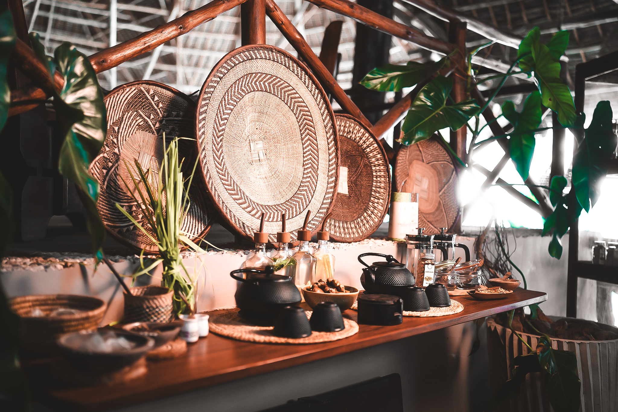 Stilvolle Tee-Station mit schwarzen Gusseisen-Teekannen, Körben und traditionellen geflochtenen Wanddekorationen.